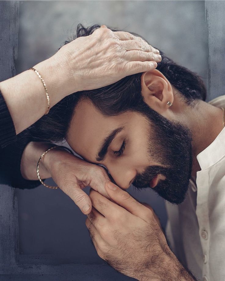 a man holding his hand to his face while looking down at the ground with his hands on his head