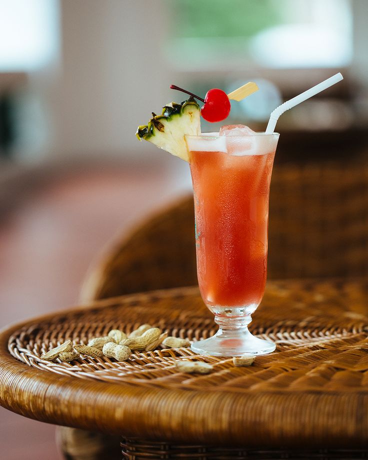 a glass filled with fruit and garnish sitting on top of a wicker table