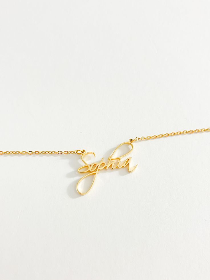 A necklace completely unique to you. Our personalised cursive name necklace is the perfect personalised accessory for you or the perfect gift for someone special. Wear your name or someone else’s around your neck every day. Our cursive font name necklace has been crafted from high-quality materials. This necklace is made to last and is suitable for everyday wear. The pendant and chain are both made of durable stainless steel, for a waterproof long lasting finish, ensuring that it will not tarnis Custom Name Pendant Necklace For Her, Personalized Yellow Gold Name Necklace As Gift For Her, Elegant Charm Necklaces With Custom Name For Personalized Gift, Elegant Customizable Name Necklace As Gift For Her, Personalized Adjustable Yellow Gold Name Necklace, Elegant Customizable Name Necklace Gift For Her, Elegant Customizable Charm Necklace As Gift For Her, Dainty Custom Name Necklace For Her, Dainty Nameplate Necklace For Her