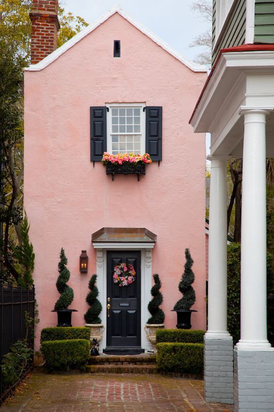 a pink house with black shutters and white trim on the front door is shown