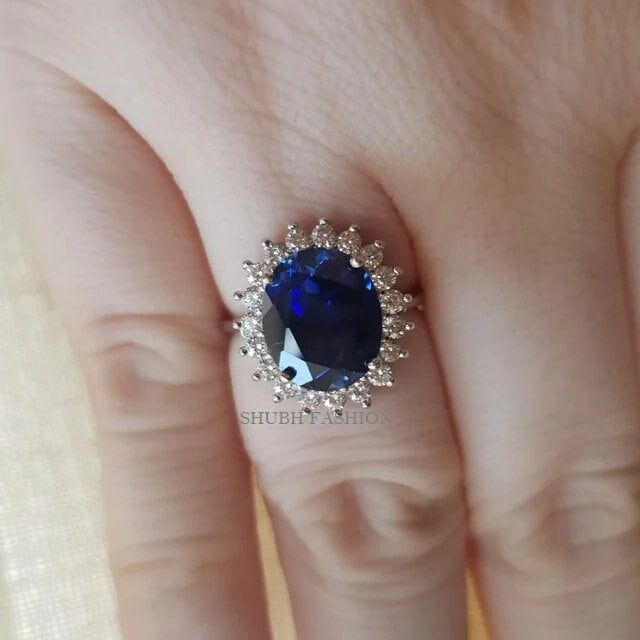 a woman's hand with a blue and white diamond ring on top of her finger