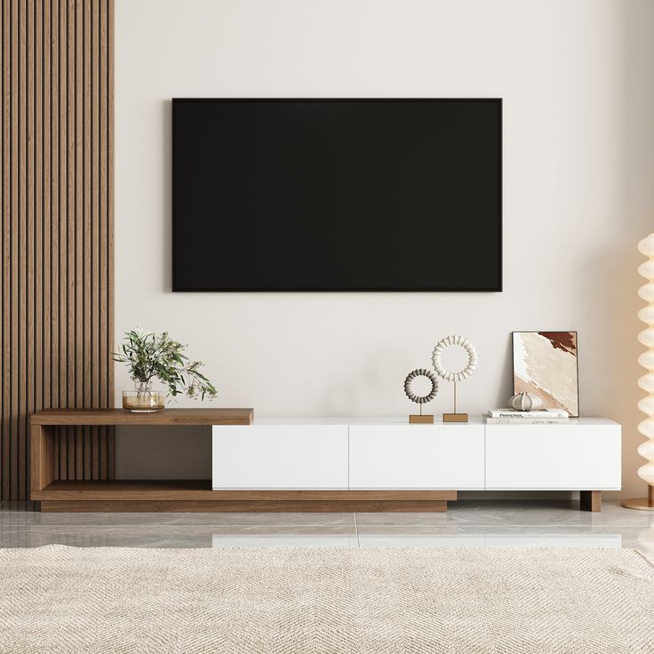 a living room with a large flat screen tv mounted on the wall above a white entertainment center