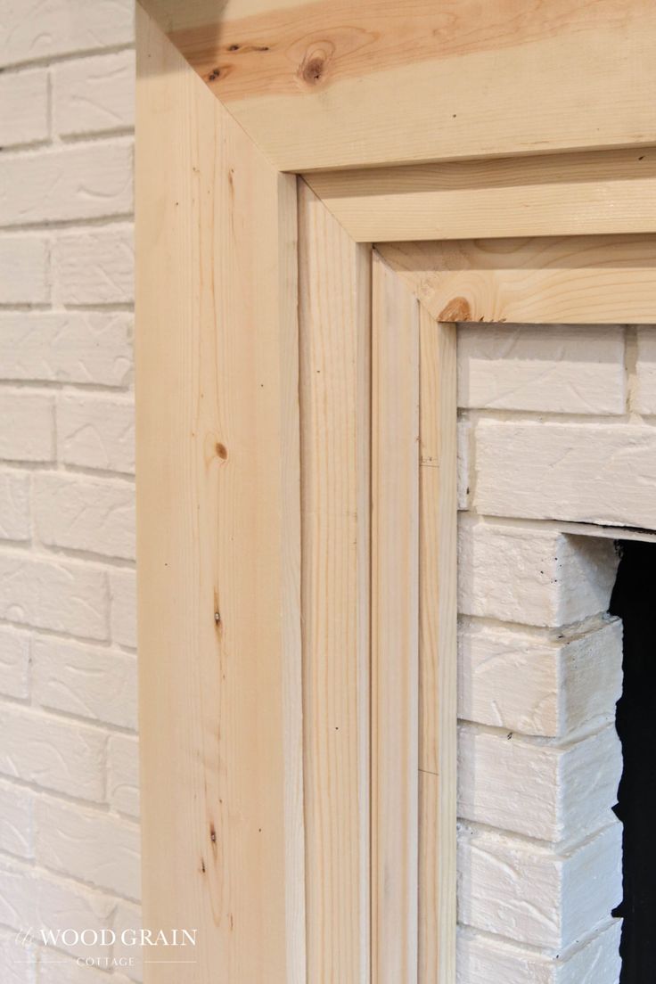 a white brick fireplace with wood trim around it