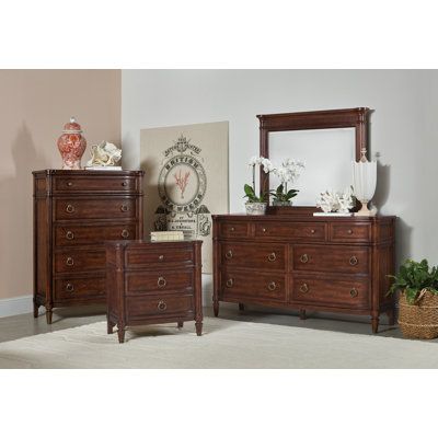 a bedroom scene with focus on the dresser, mirror and bed sideboard in the foreground