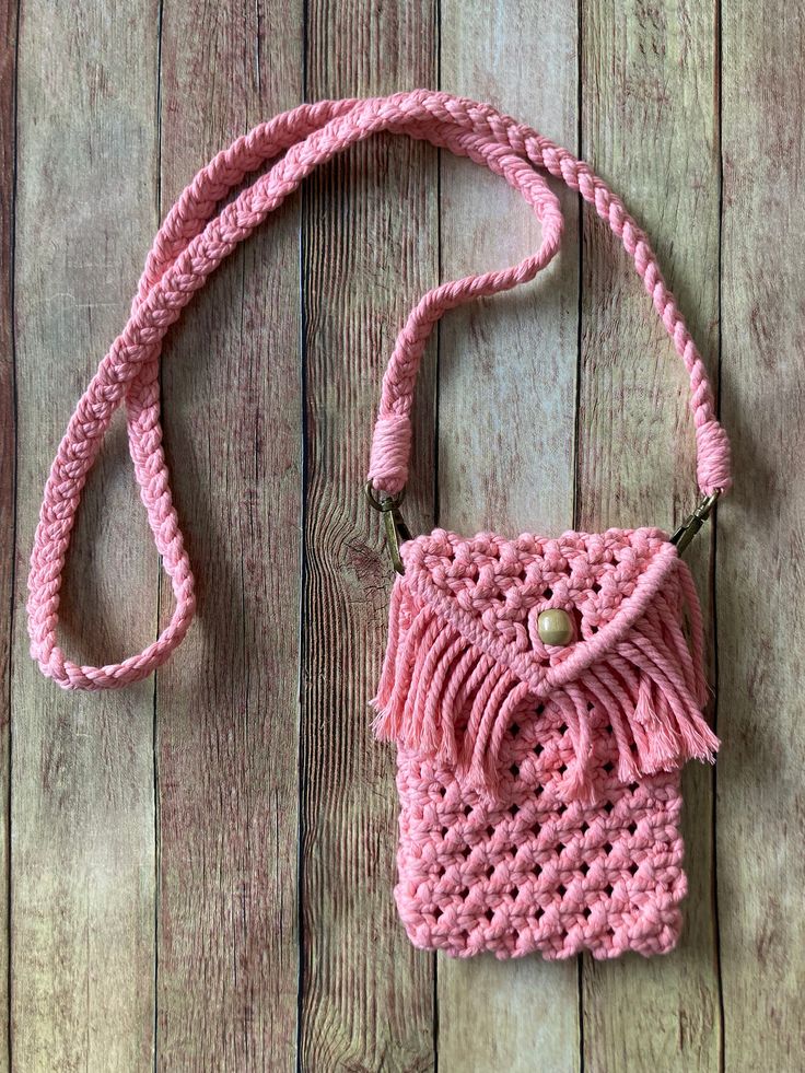 a pink crocheted purse sitting on top of a wooden floor next to a string