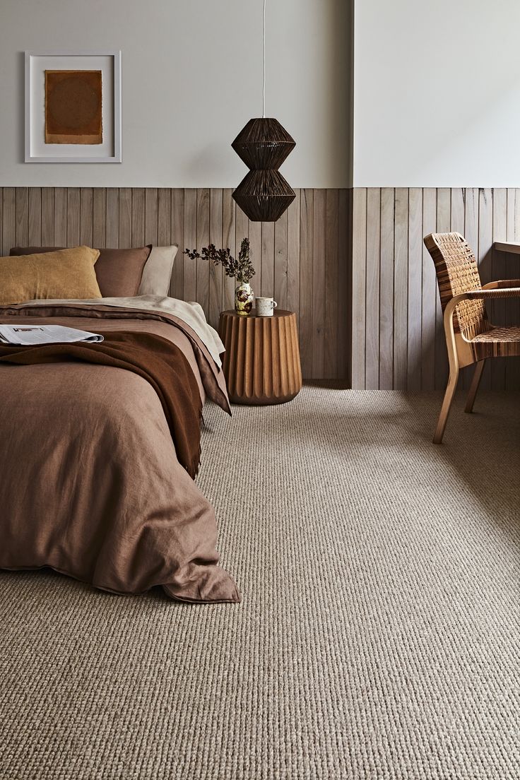 a bed sitting in a bedroom next to a wooden headboard and table with a plant on it