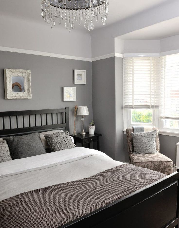 a bedroom with gray walls and white trim on the bed, chandelier in the corner