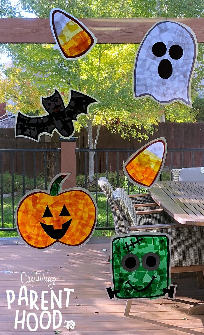 paper cut out pumpkins and ghost faces hanging from a pergolated porch