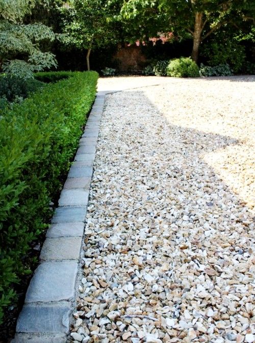 a graveled path with trees and bushes in the background