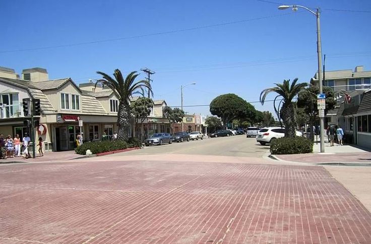 an empty street with cars parked on both sides and palm trees in the middle of it