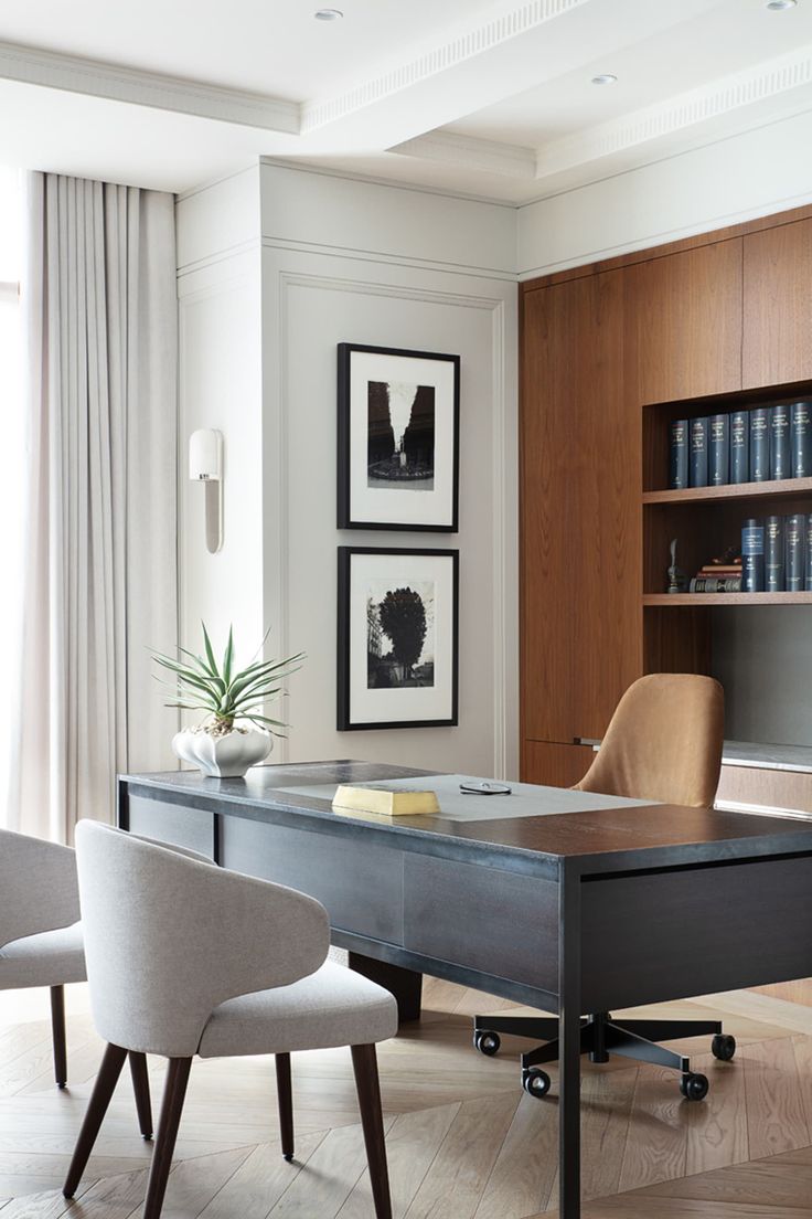 an office with two chairs and a desk in front of a bookcase filled with books