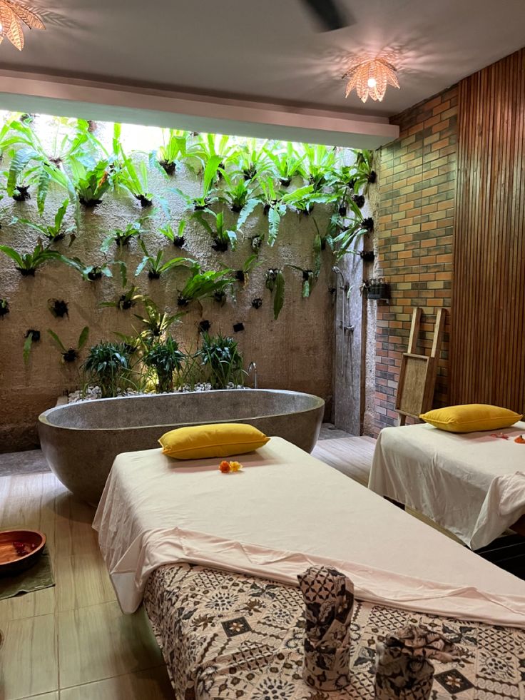 two beds in a room with plants on the wall and a bathtub next to them