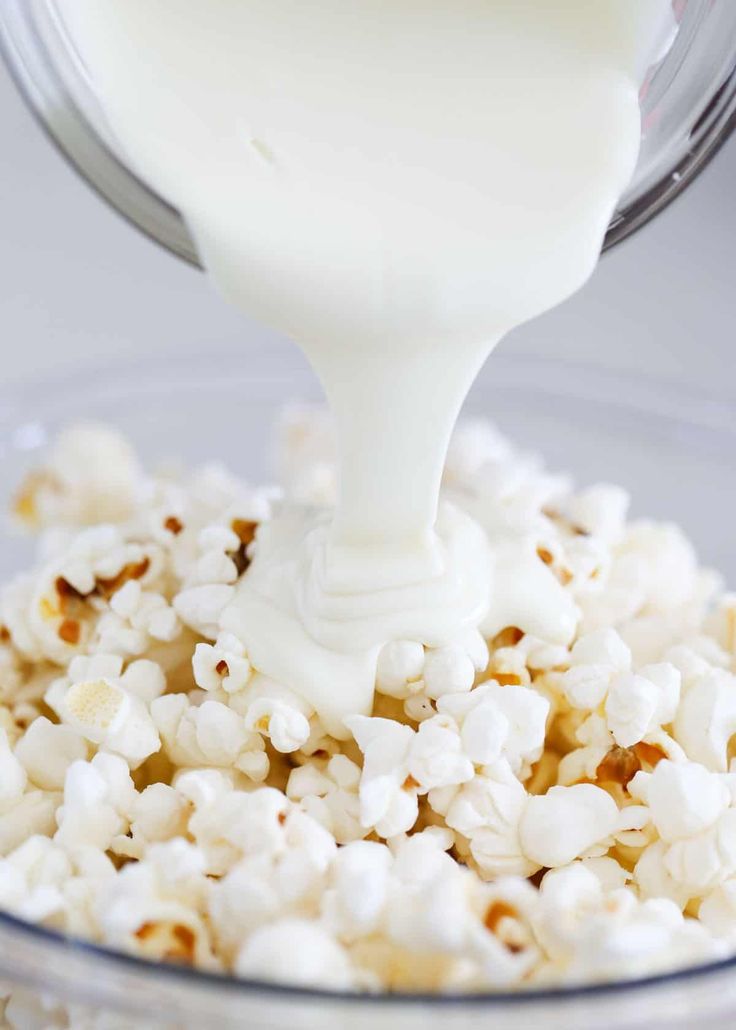 a glass bowl filled with popcorn and milk being poured into the bowl to make it pop