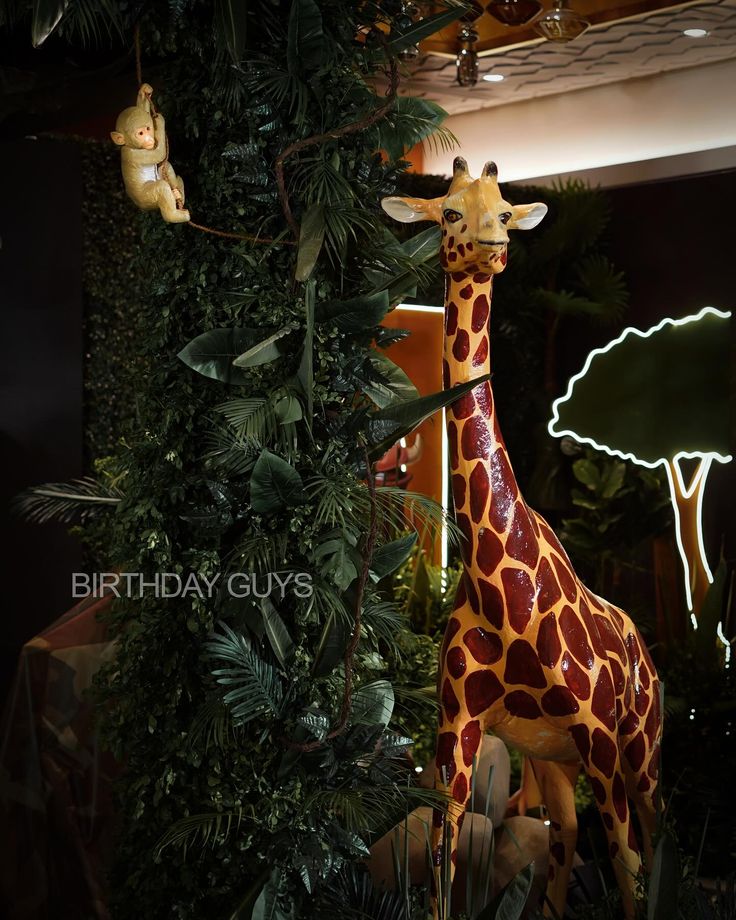 a giraffe statue sitting next to a lush green tree