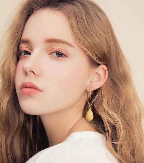 a close up of a person wearing earrings and a white t - shirt