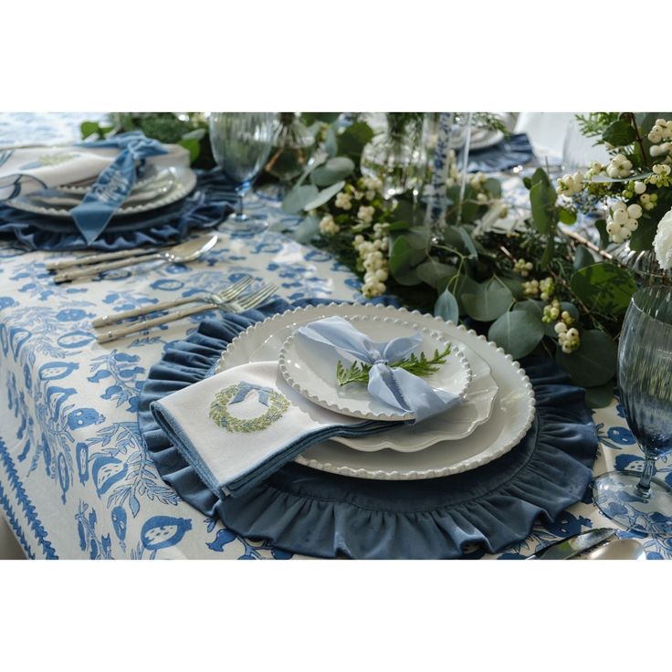 a blue and white table setting with flowers in vases on the side, plates and napkins