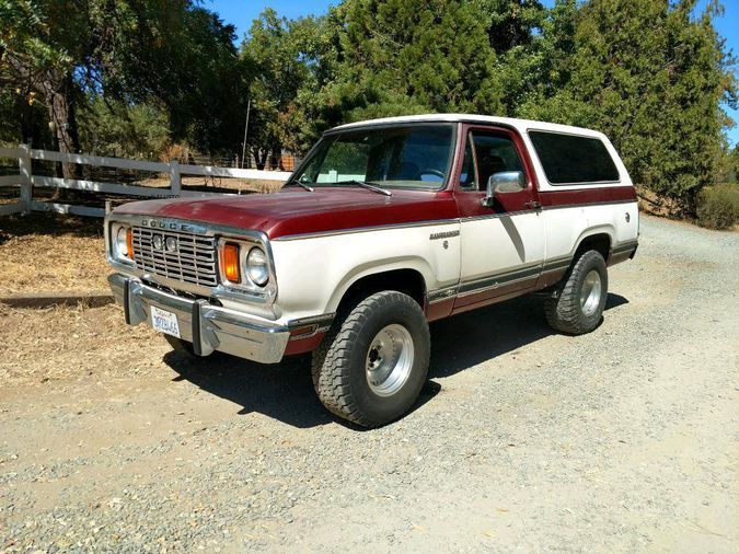 a red and white pick up truck parked on the side of a dirt road next to trees