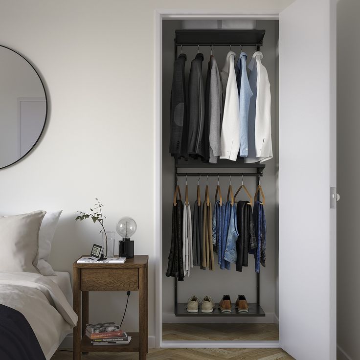 an open closet with clothes and shoes hanging on the wall, next to a bed