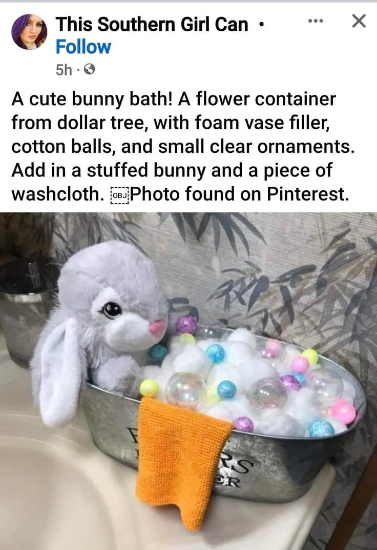 a white stuffed animal sitting in a tub filled with bath balls and an orange towel