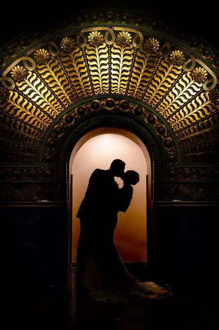 the silhouette of a bride and groom in front of an ornate archway