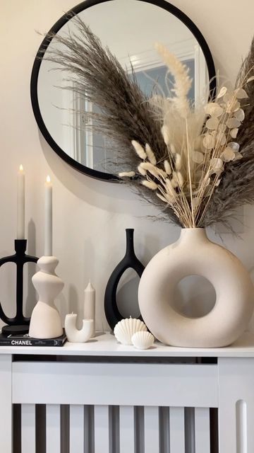 a white table topped with a vase filled with flowers and candles next to a mirror