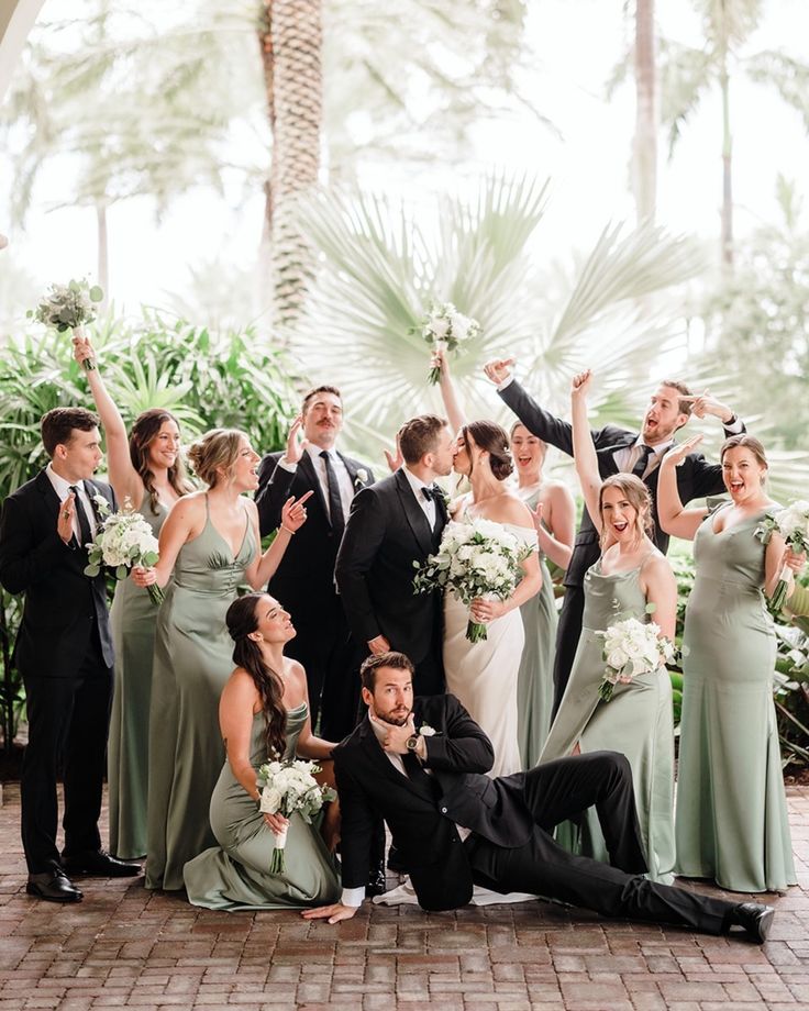 a group of people standing and sitting next to each other in front of palm trees