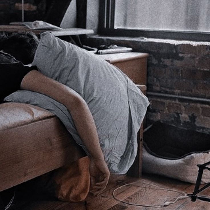 a woman laying on top of a bed in a bedroom next to a brick wall