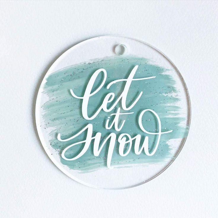 a round ornament with the words let it snow written in cursive writing