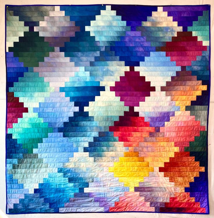 a multicolored quilt is hanging on the wall