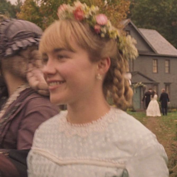 a woman with braids and flowers in her hair standing next to another woman wearing a white dress