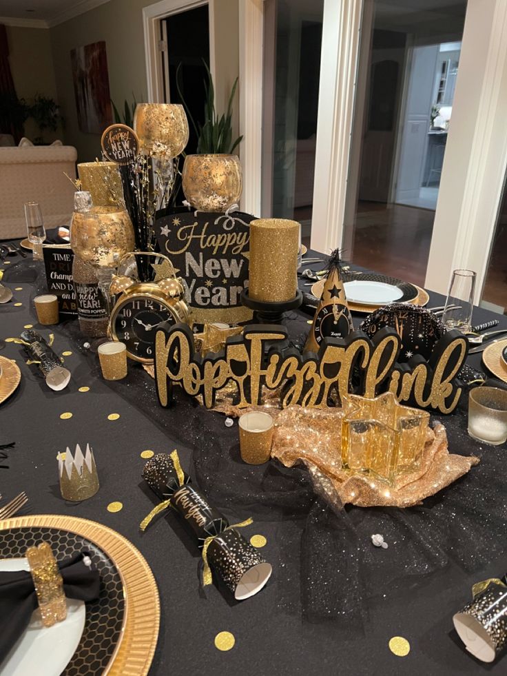 a black and gold party table setting with confetti, candles, napkins and plates