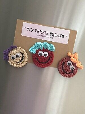 three crocheted magnets with funny faces on them are hanging from a refrigerator