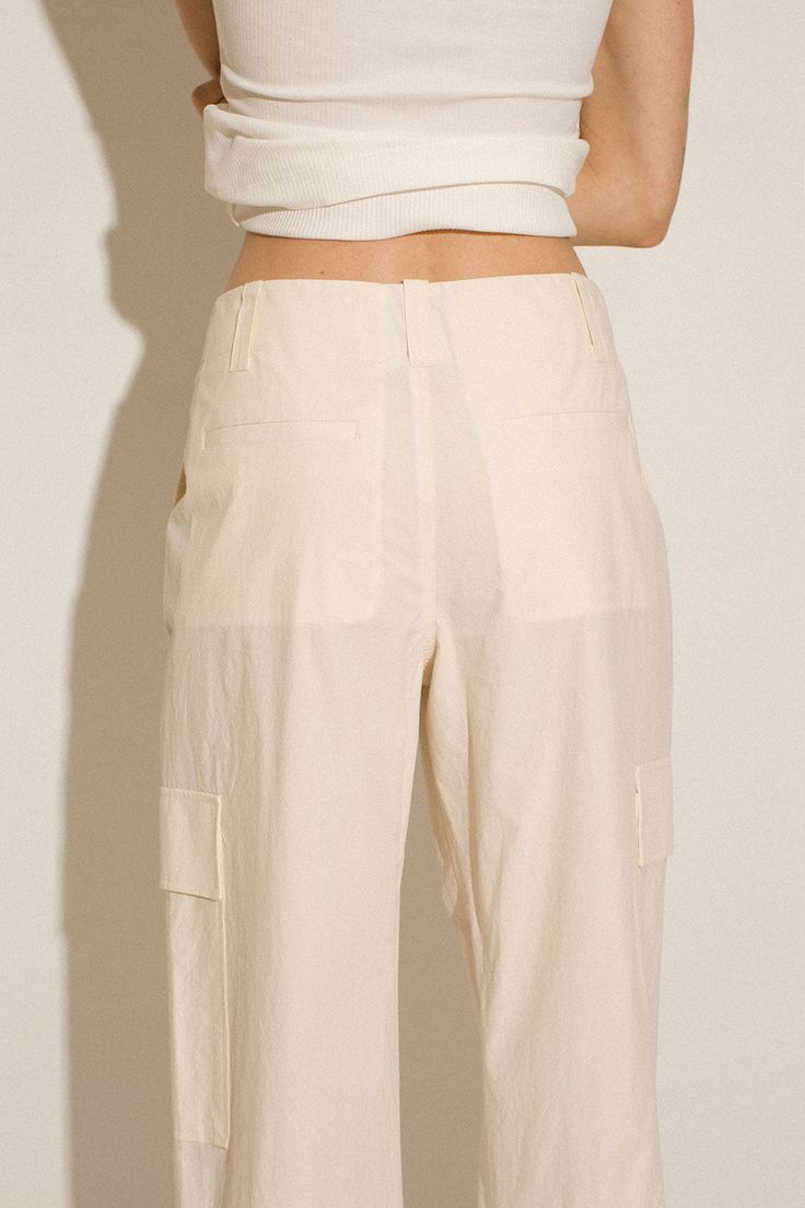 Loosely tailored cargo pant in a soft yet structured cotton. Straight leg with tie at ankle, cinch for a more tapered silhouette. Side pockets and oversized patch pockets above knee. Made in New York City. Fabric is 100% cotton. Ella is 6' tall, 35" bust, 26" waist, 36" hip, and is wearing a size S. Cotton Cargo Shorts With Multiple Pockets For Workwear, High-waisted Relaxed Fit Cargo Pants With Patch Pockets, Beige Ankle-length Cargo Pants For Work, Cotton Cargo Shorts With Pockets For Work, Beige Cargo Pants With Multiple Pockets For Work, High-waisted Parachute Pants With Multiple Pockets For Work, Spring Straight Cargo Pants With Flap Pockets, Spring Workwear Cargo Shorts With Side Pockets, Beige Cotton Cargo Jeans For Work