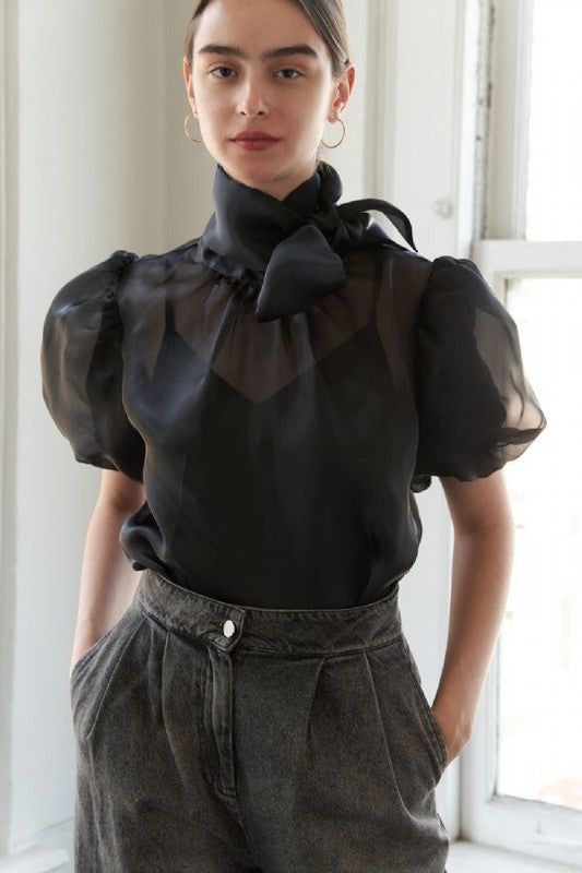 A solid woven organza blouse featuring front bow tie, short puff sleeve, back neck button closure and cami Details: SELF: 90% POLYESTER 10% SPANDEX LINING:100% POLYESTER Size & Fit - Model is 5'9" And Wearing Size Small - Measurements Taken From Size Small Approx. center front length: 9 1/4". Organza Top Outfit, Organza Blouses, Organza Top Styles, Organza Outfit, Organza Jacket, Organza Bow, Polka Dot Midi Skirt, Black Attire, Bow Tie Blouse