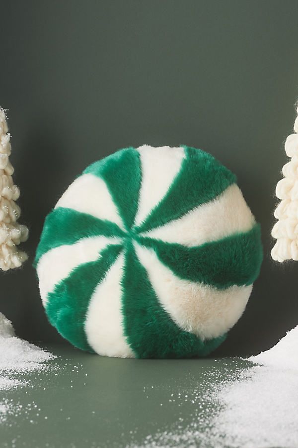 a green and white peppermink candy cane in the snow