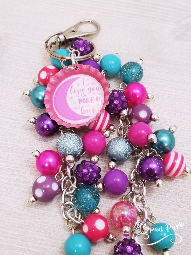 a close up of a key chain on a white surface with beads and charms attached to it