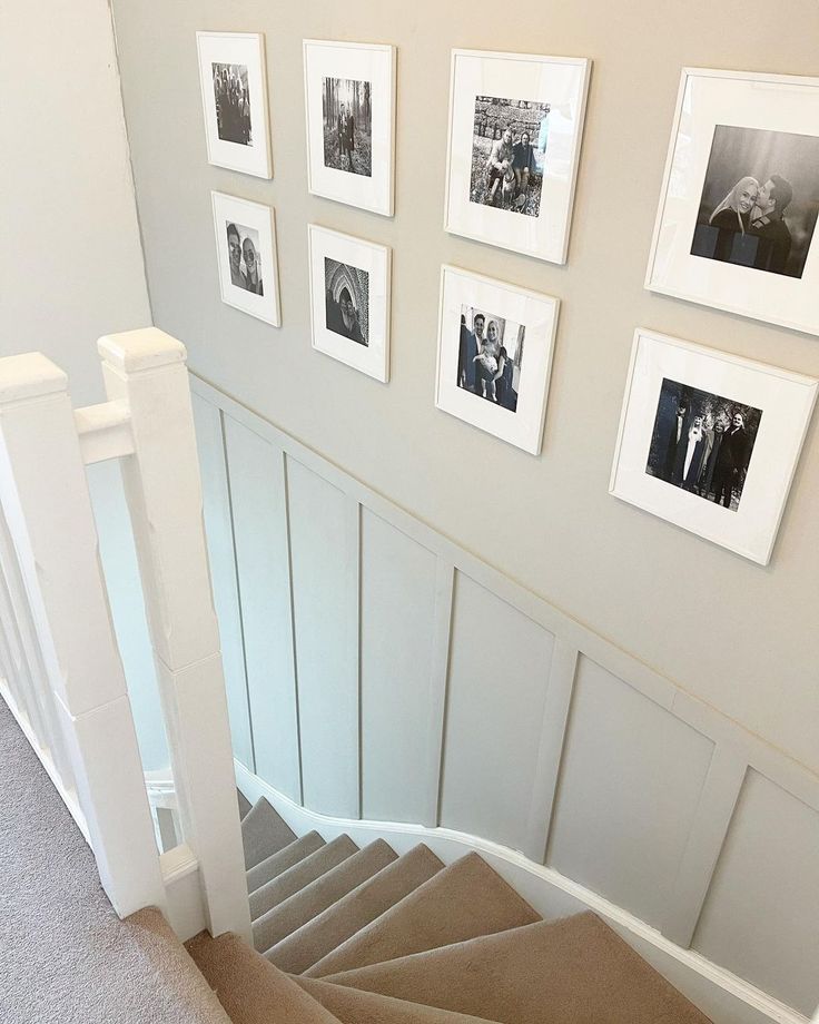 a staircase with pictures on the wall and carpeted steps leading up to an upstairs landing