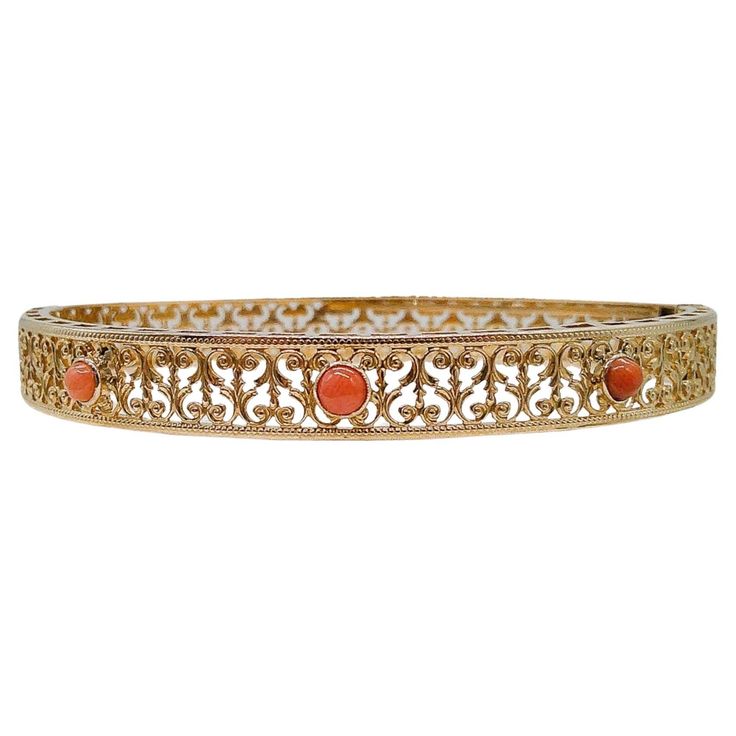 This 14k gold coral bangle is a contemporary piece. Three stunning coral stones take center stage, each delicately cradled in the warm embrace of 14k gold. Their gentle hues bring to mind the soft caress of the sea breeze and the sun's gentle kiss. The coral stones are framed by extensive filigree and milgrain accents that dance like linen in the summer breeze. Like delicate tendrils of dreams, the filigree wraps the entire bangle, creating an enchanting play of light and shadow that dances with your every movement. Each stroke of filigree is a testament to our artisans' dedication to crafting wearable art. Whether you're dressing up for a special occasion or simply looking to infuse everyday life with a touch of magic, our Contemporary Coral Bangle is the perfect companion. This bangle me Coral Bangles Gold, Coral Bangles, Coral Bracelet, Dance With You, Coral Stone, Sea Breeze, Summer Breeze, Gold Jewellery Design, Jewellery Design