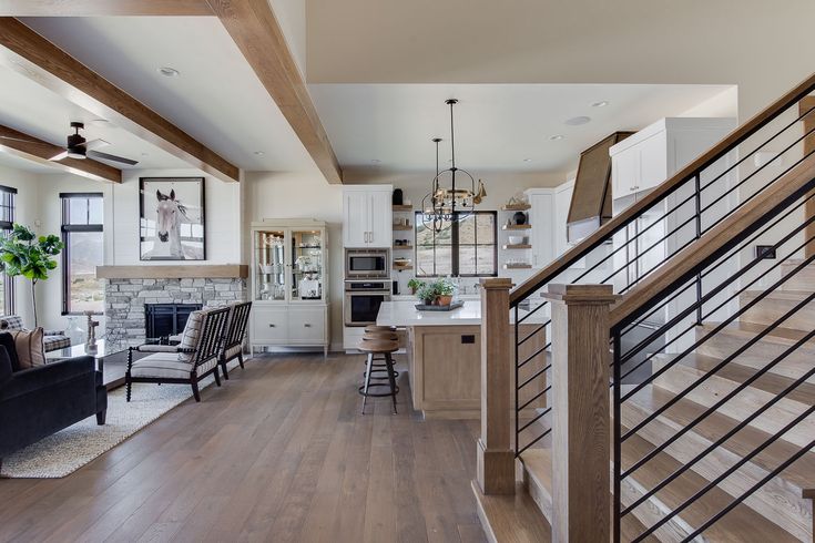 an open concept kitchen and living room with wood floors, white cabinets, and stairs