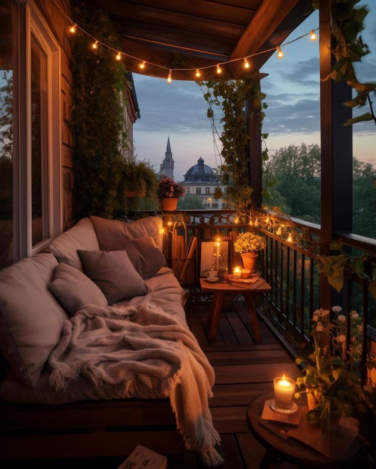 a porch with lights strung from the ceiling and pillows on it, next to a couch that is covered in blankets