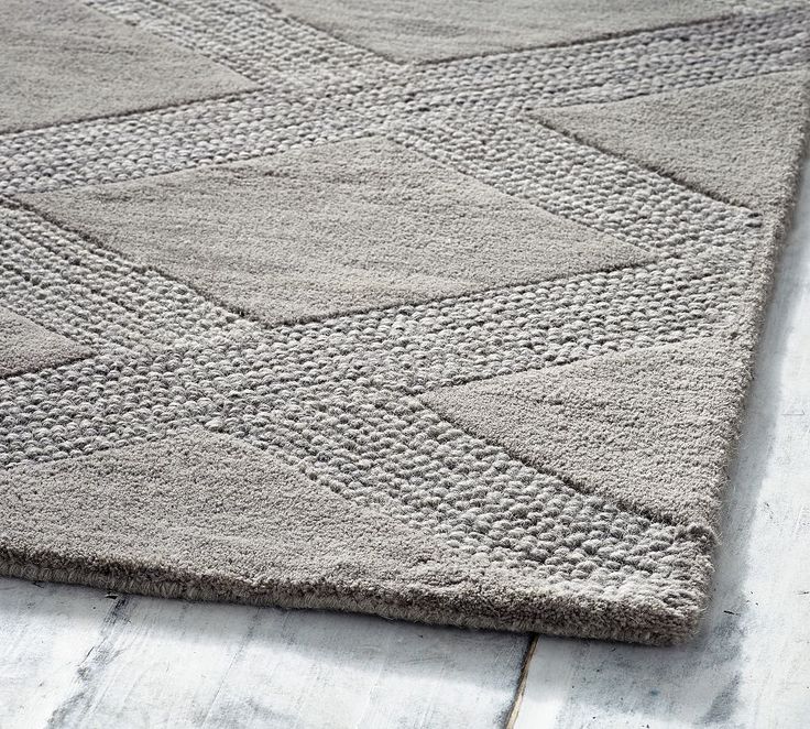 a gray rug on top of a wooden floor with white tiles and wood floors in the background