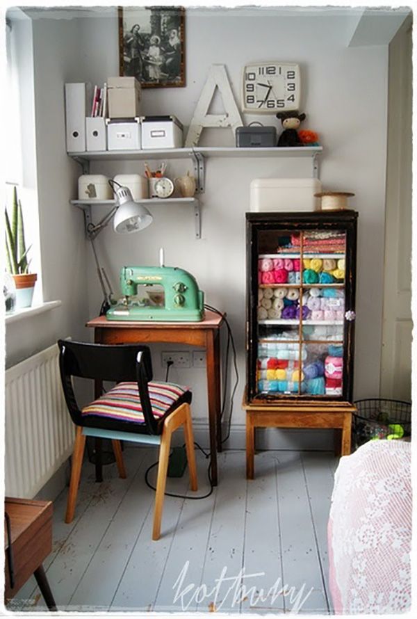 a sewing machine sitting next to a desk in a room with white walls and wooden floors