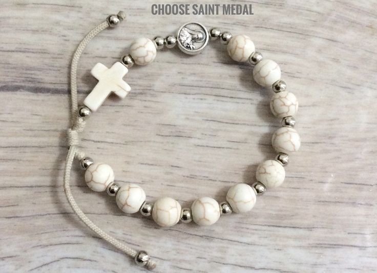 Saint medal rosary bracelet is made with 8mm white faux howlite beads and cross,silver tone spacer beads,cross and 1cm silver tone saint medal of your choice. For Men and Women . Adjustable cording ,fits a wrist size from 6.5 x7.5 inches. Metal parts made in Italy. Hand made in Medjugorje. A nice gift for a loved one or a statement of faith to wear yourself. For more similar items and different colors visit our store: https://www.etsy.com/shop/Thelightjewelry?ref=seller-platform-mcn Nickel-free Round Rosary Bracelet Gift, White Spiritual Cross Jewelry And Charms, White Cross Jewelry With Miraculous Medal, Adjustable White Rosary Bracelet, White Hypoallergenic Rosary Bracelet With Round Beads, Adjustable White Rosary As Gift, Adjustable Round Rosary As Gift, White Adjustable Hypoallergenic Rosary Bracelet, Adjustable Rosary Bracelet With Miraculous Medal For First Communion