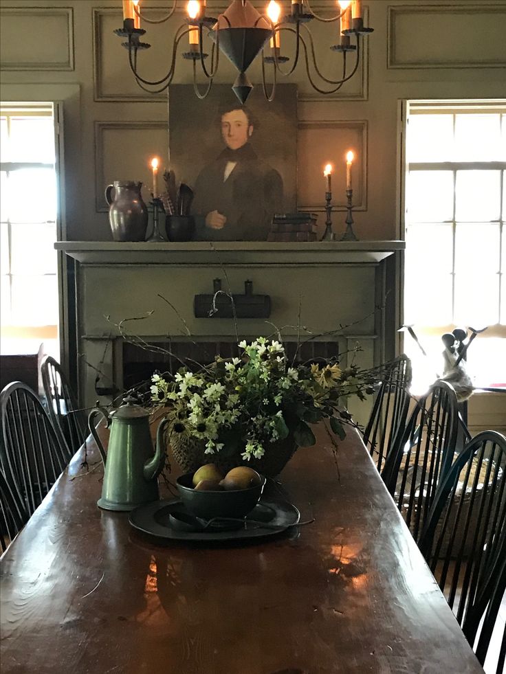 a dining room table with candles on it and a painting above the fireplace in the background