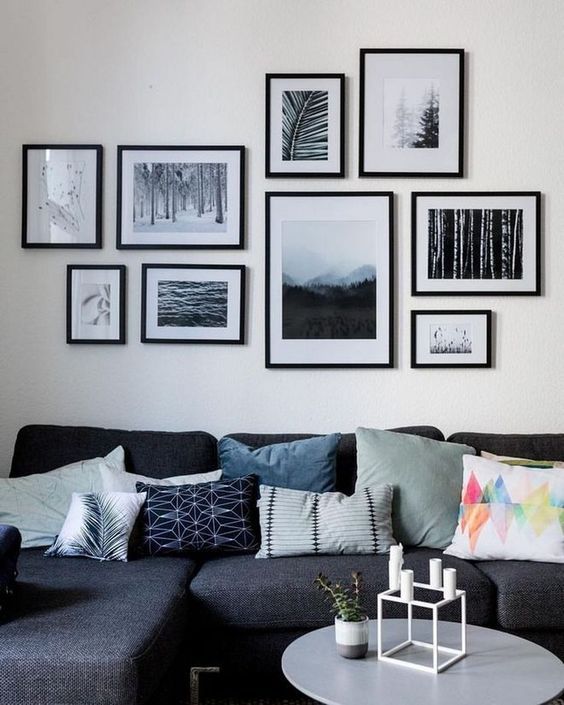 a living room filled with lots of framed pictures on the wall above a gray couch