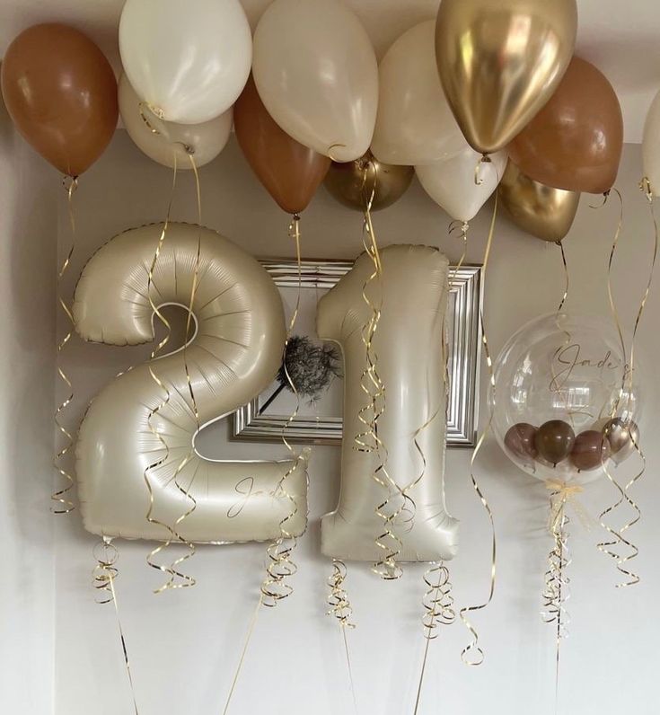 balloons and streamers in the shape of numbers are hanging on a wall above a framed photograph