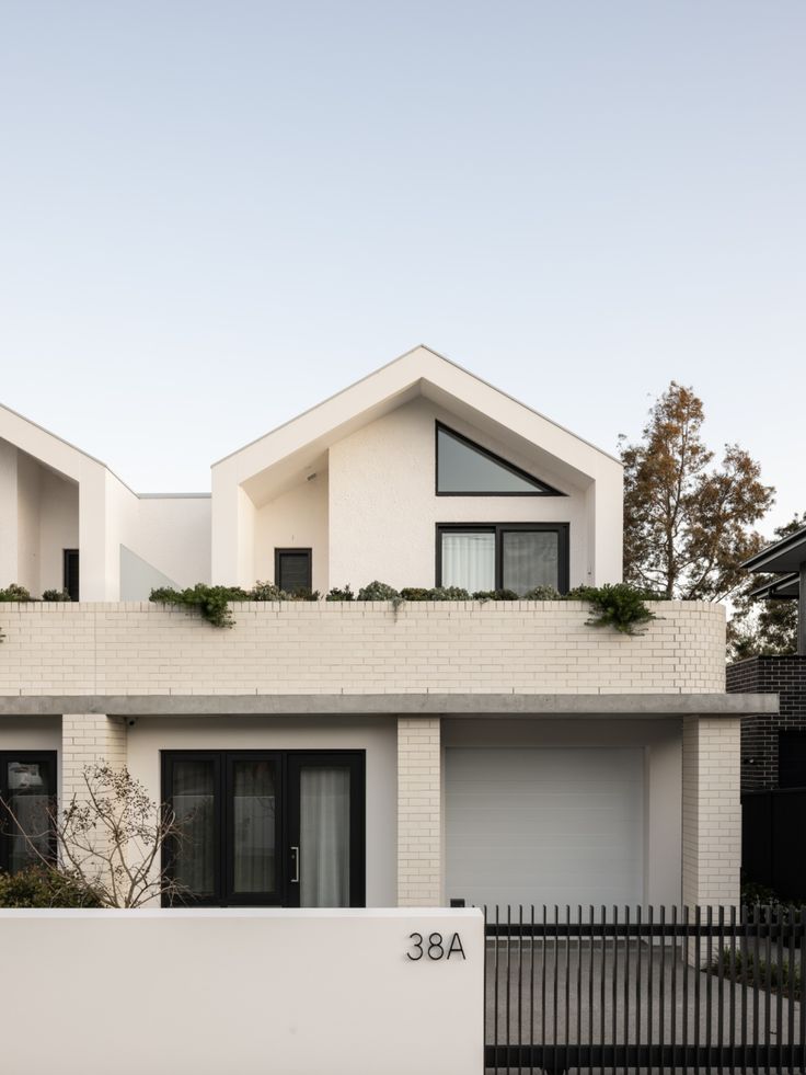 two houses with white walls and black fences