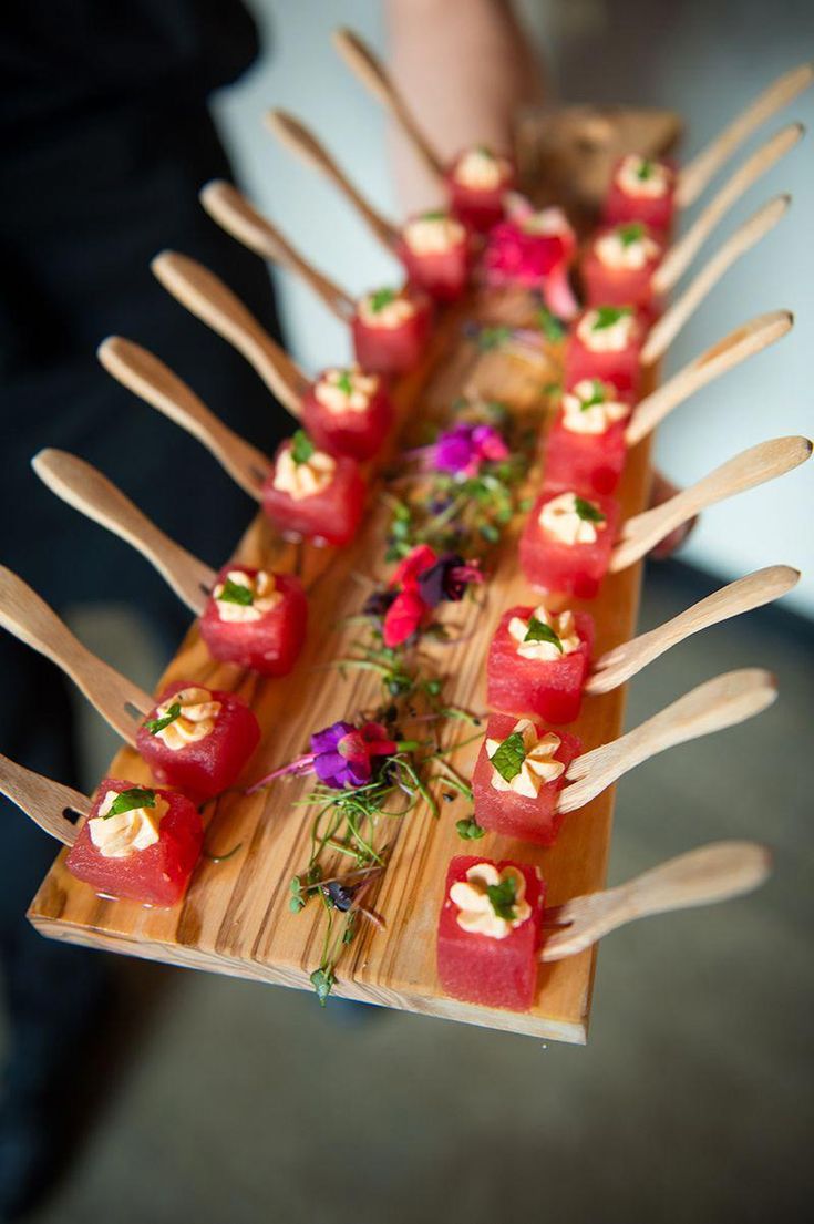 there are many small pieces of sushi on the wooden platter with utensils