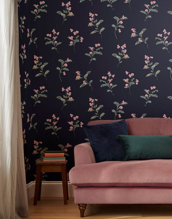 a pink couch sitting in front of a purple wallpapered with flowers and leaves