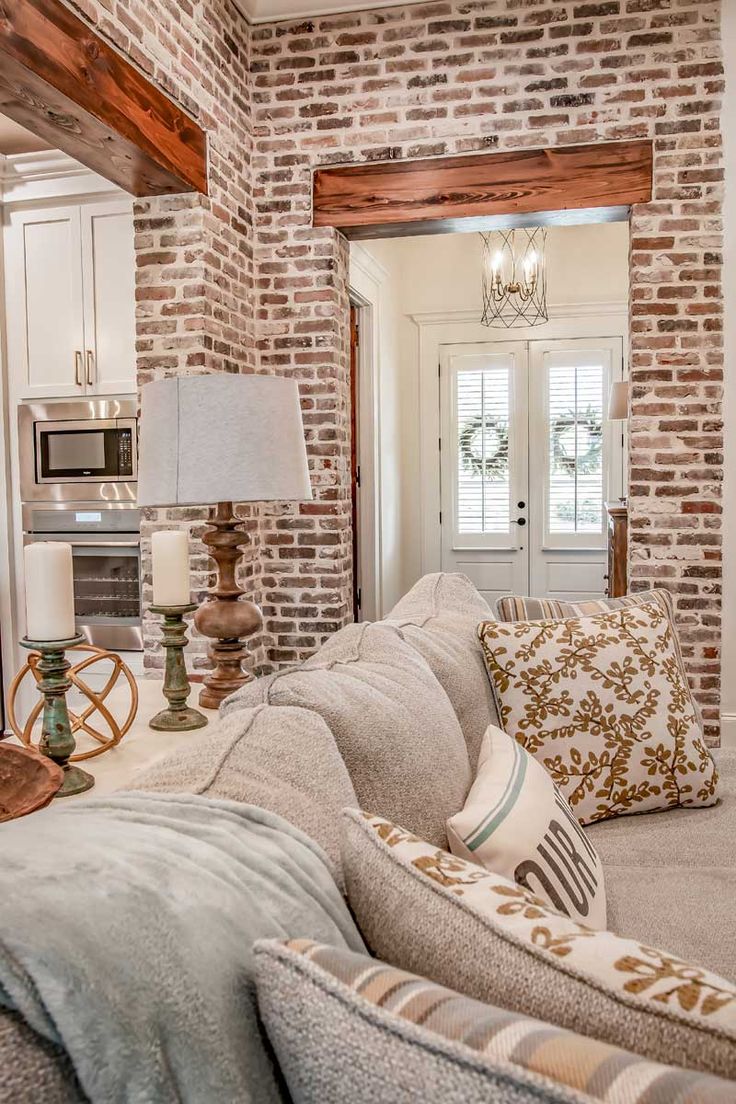 a living room filled with furniture next to a kitchen and dining room table in front of a brick wall